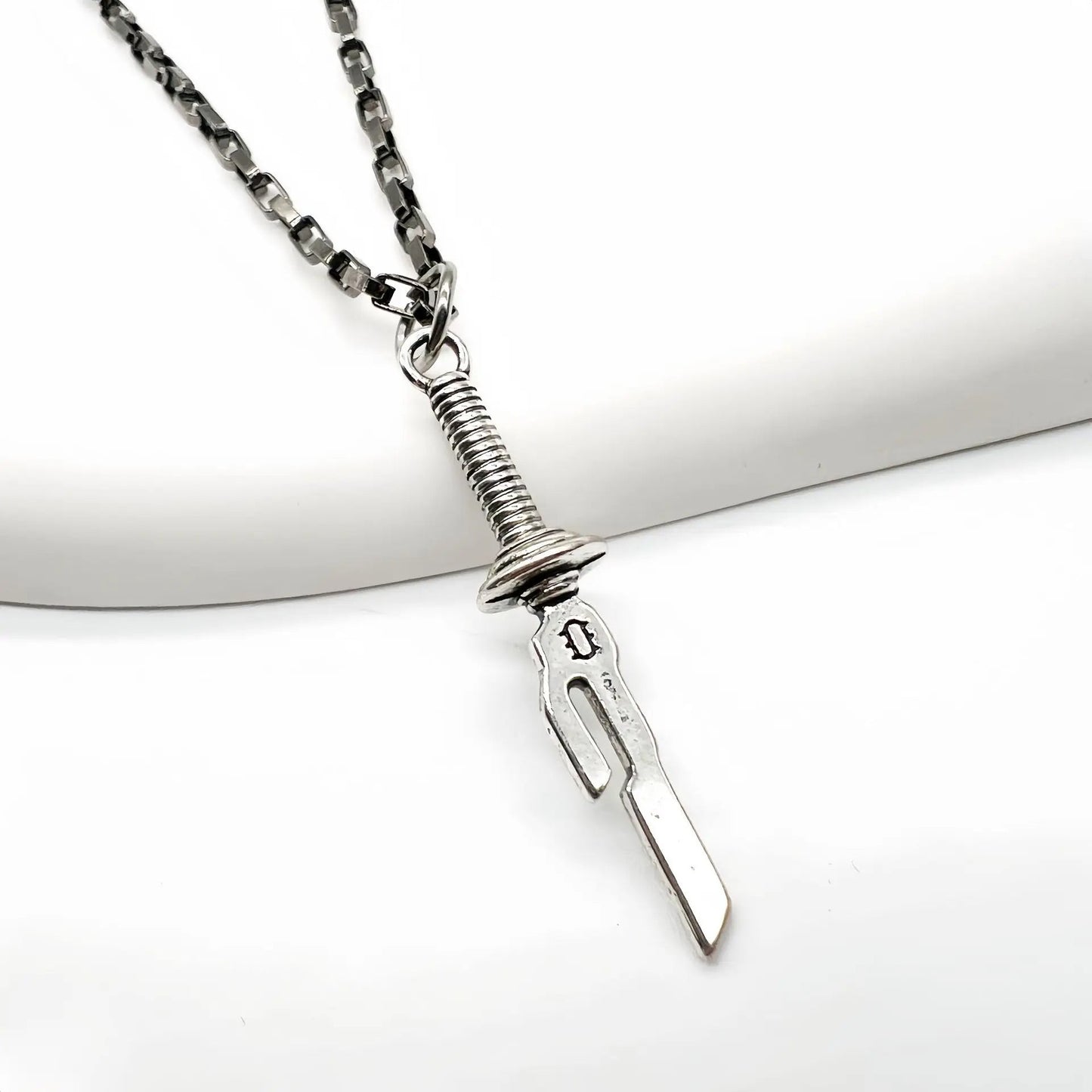 This necklace features a pendant shaped like a dagger. Here's a description of the necklace: