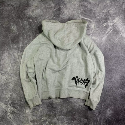 Back view of a heather grey heavyweight zip-up hoodie featuring the Berserk logo in black Katakana on the lower right hem.