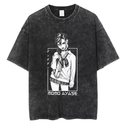 A black t-shirt with a distressed print of Momo Ayase from the manga series "Dandadan." She is depicted in a seductive pose, with the Japanese text "タツヤ" (Tatsuya) written above her. The text "MOMO AYASE" is written in bold letters below the image.