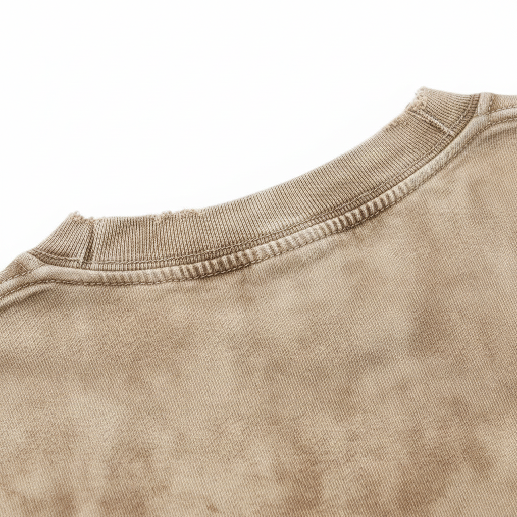 Close up of a distressed, frayed ribbed crewneck collar on a vintage brown 240 GSM heavyweight cotton t-shirt.