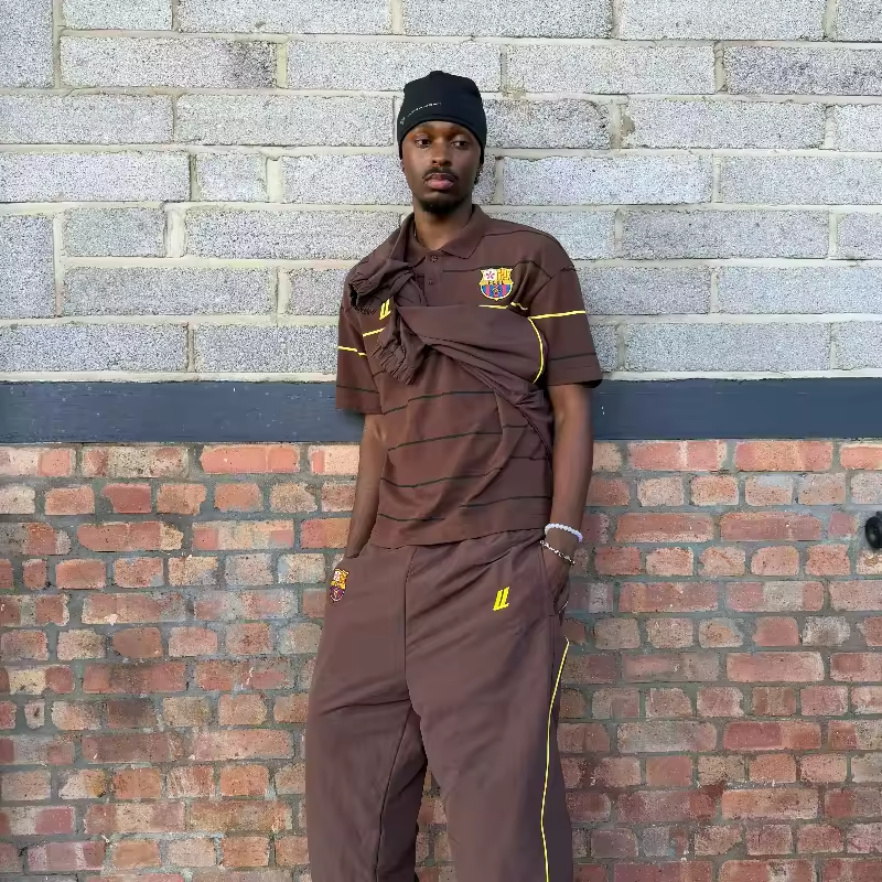 Model wearing the Mocha brown earth-tone striped oversized heritage polo with the FCUL embroidered crest.