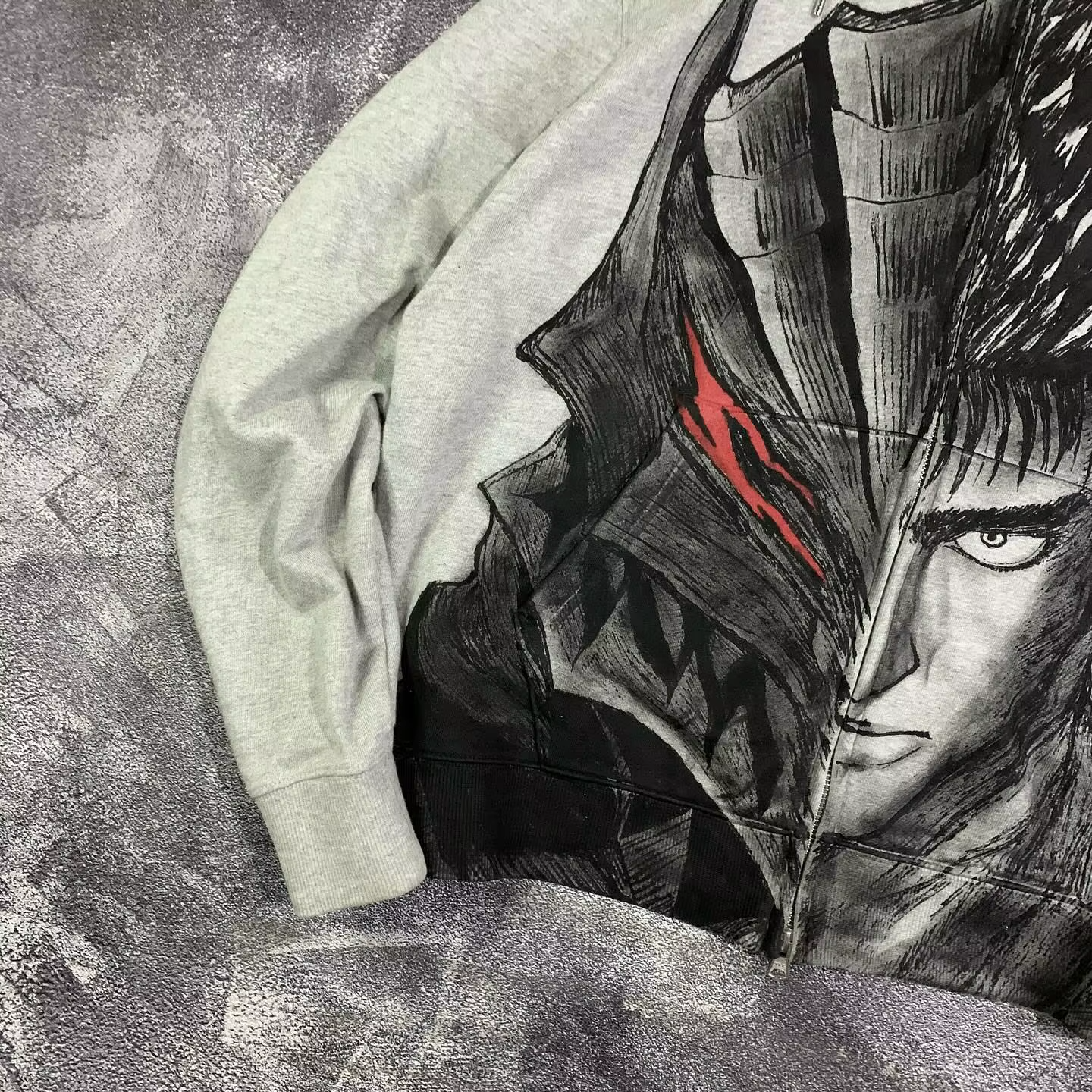 Detailed close-up of the Guts and Berserker Armor split graphic on a heather grey streetwear hoodie.