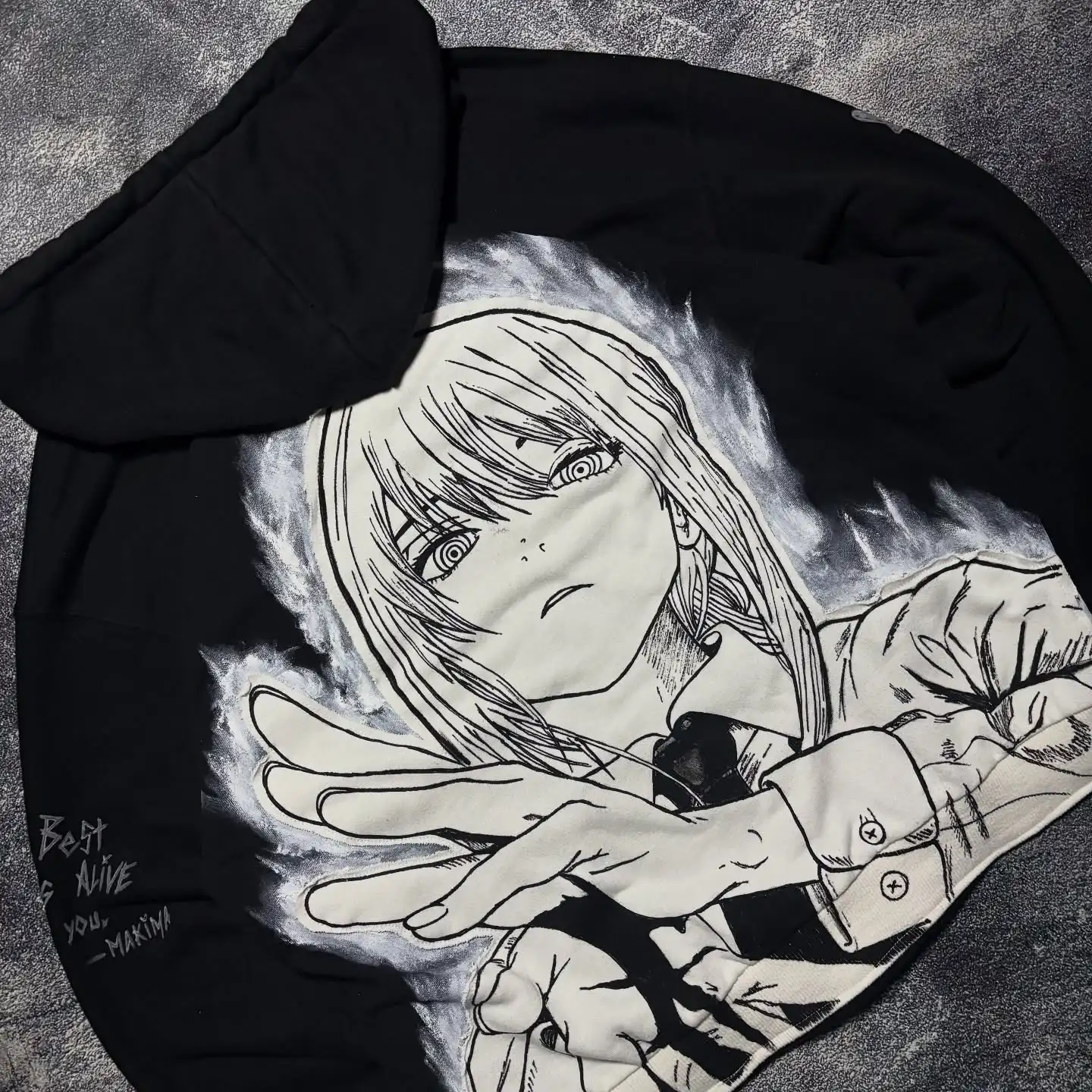 Angled view showing the Makima back graphic and custom sleeve text embroidery on a black streetwear zip-up hoodie.