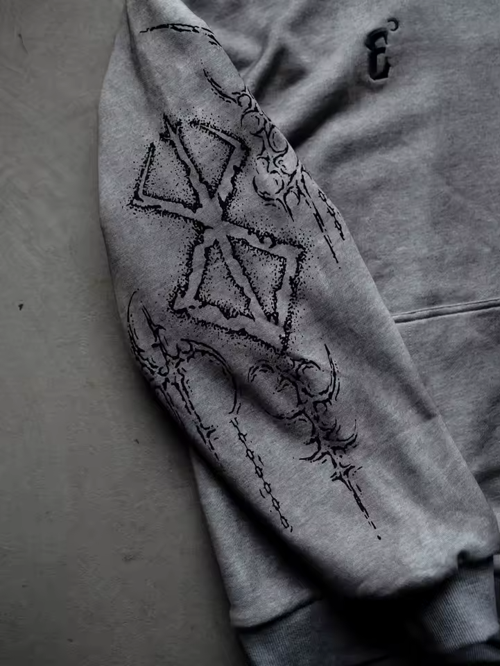 Close-up of the oversized Berserk Brand of Sacrifice graphic printed on the sleeve of a heather grey heavyweight hoodie.