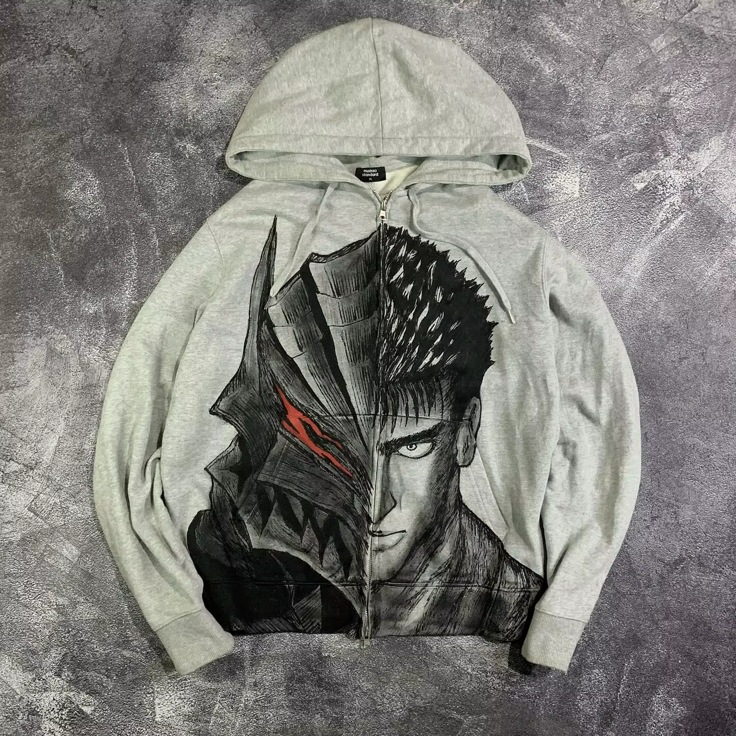 Front view of a heather grey zip-up hoodie featuring a split-face graphic of Guts and the Berserker Armor with a glowing red eye.