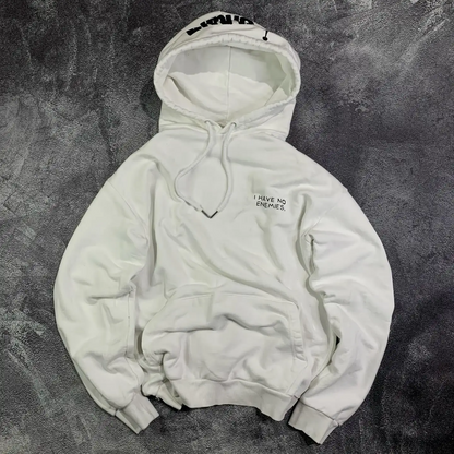 Front view of a white oversized heavyweight pullover hoodie featuring minimalist 'I have no enemies' chest typography by SkaiiyPrints