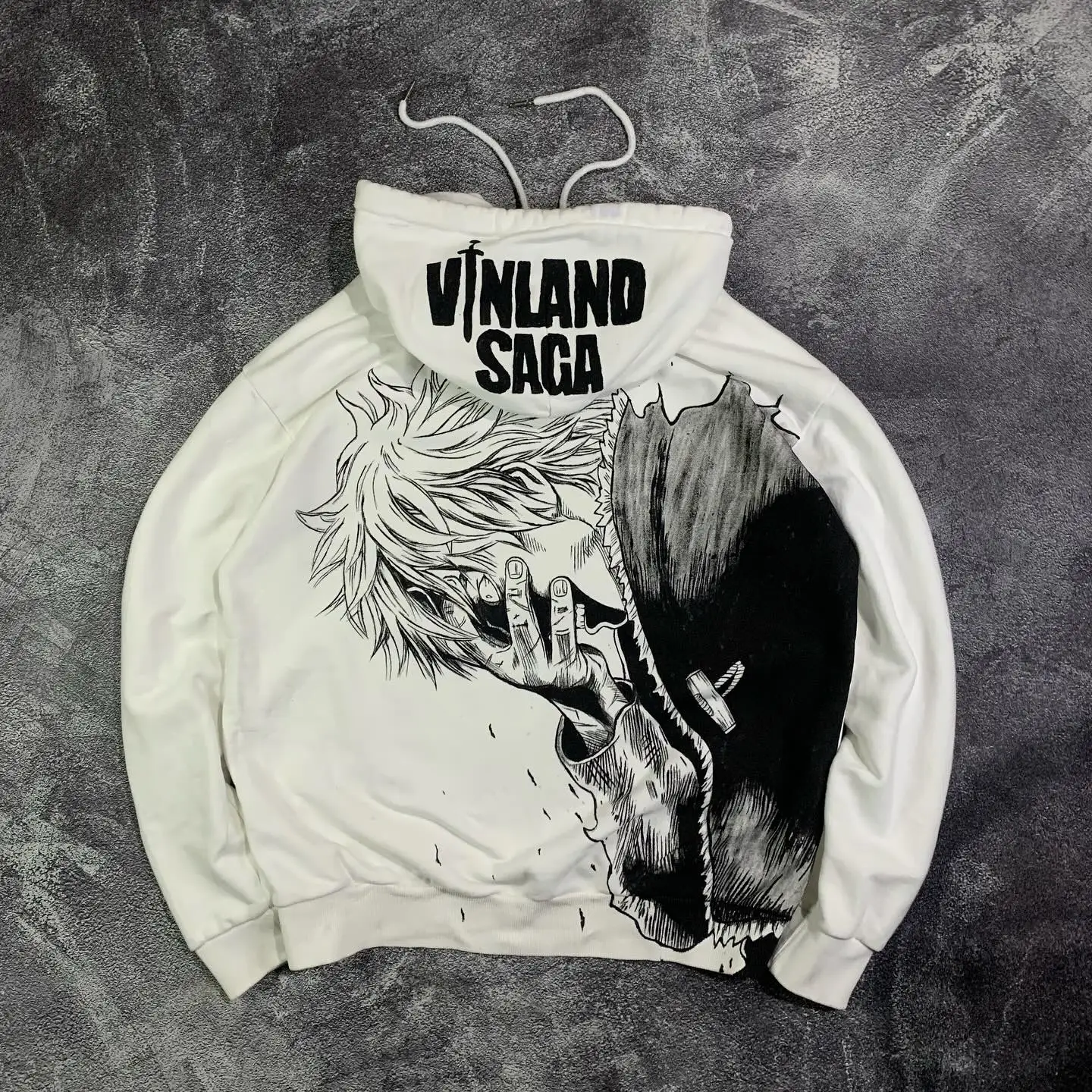 Flat lay of the back of a white streetwear hoodie featuring a massive Thorfinn manga portrait graphic and a printed hood.