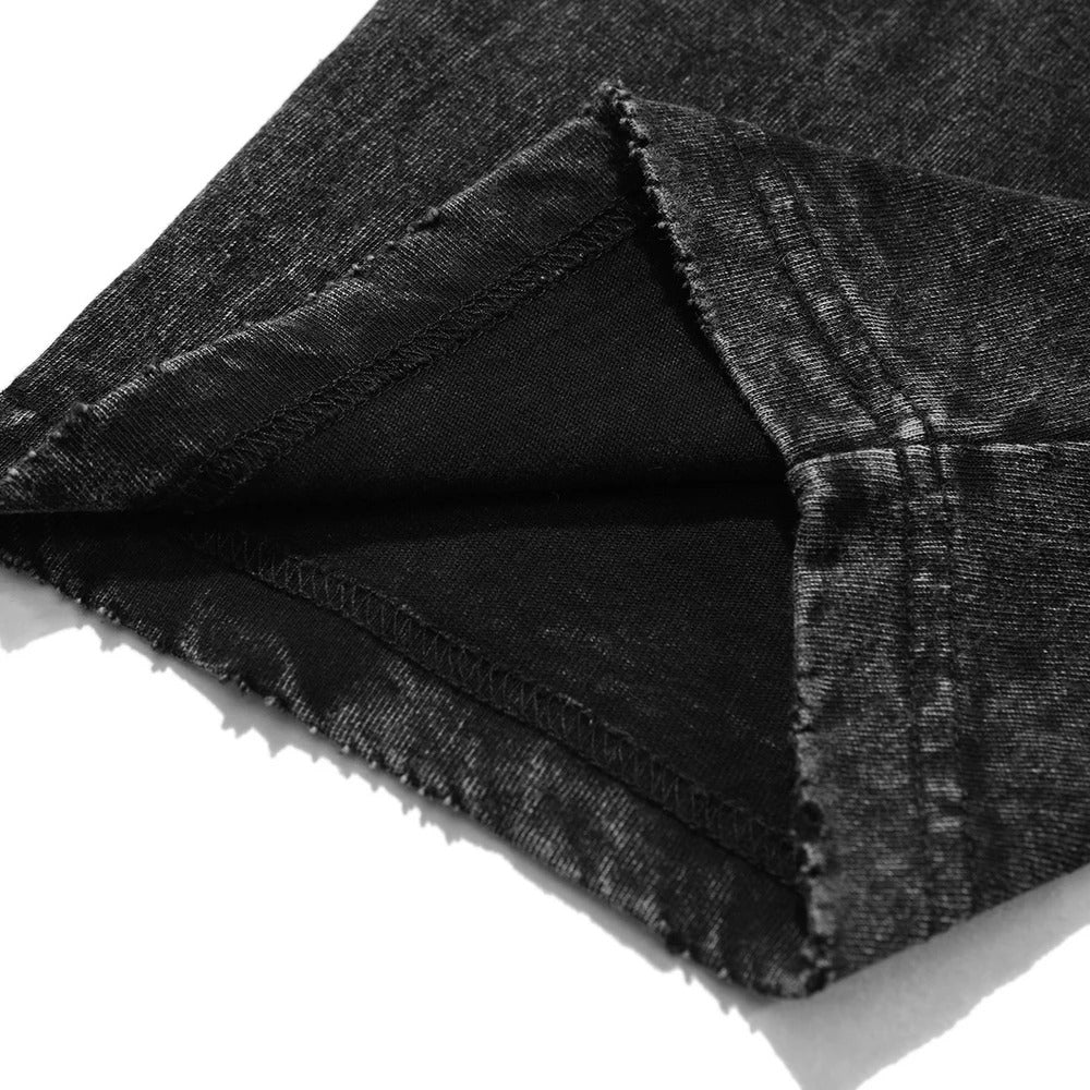 Macro view of the double-needle stitching and distressed bottom hem on a premium oversized vintage black t-shirt